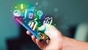 A hand holding a smartphone with colorful icons on it.